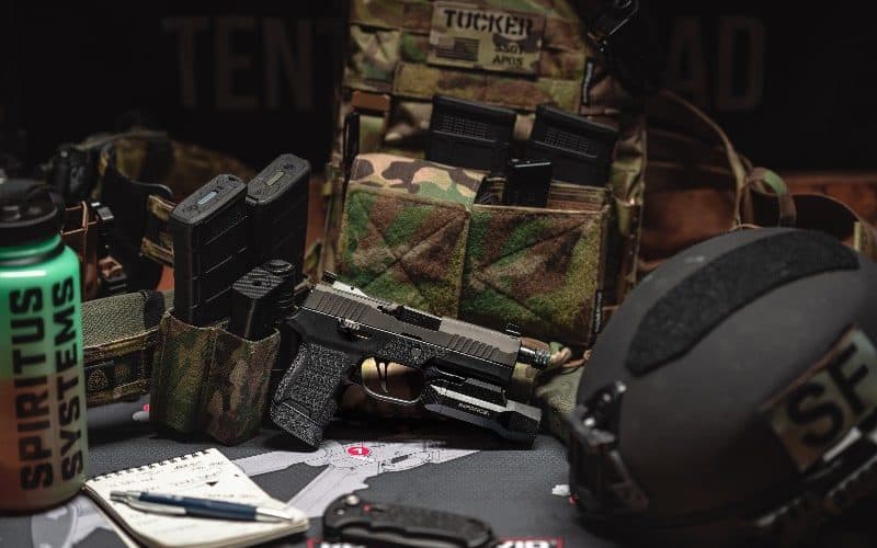 Airsoft equipment and a camouflage plate carrier laid out for packing