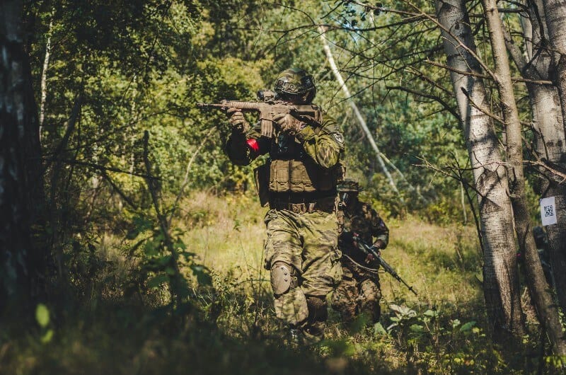 two men playing airsoft milsim in forest in summer